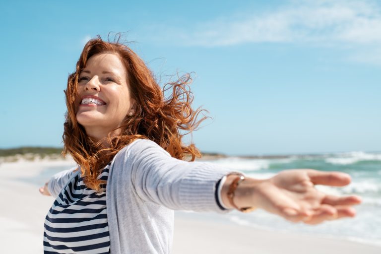 Red-haired woman looking vibrant with health and wellbeing on a sunny beach